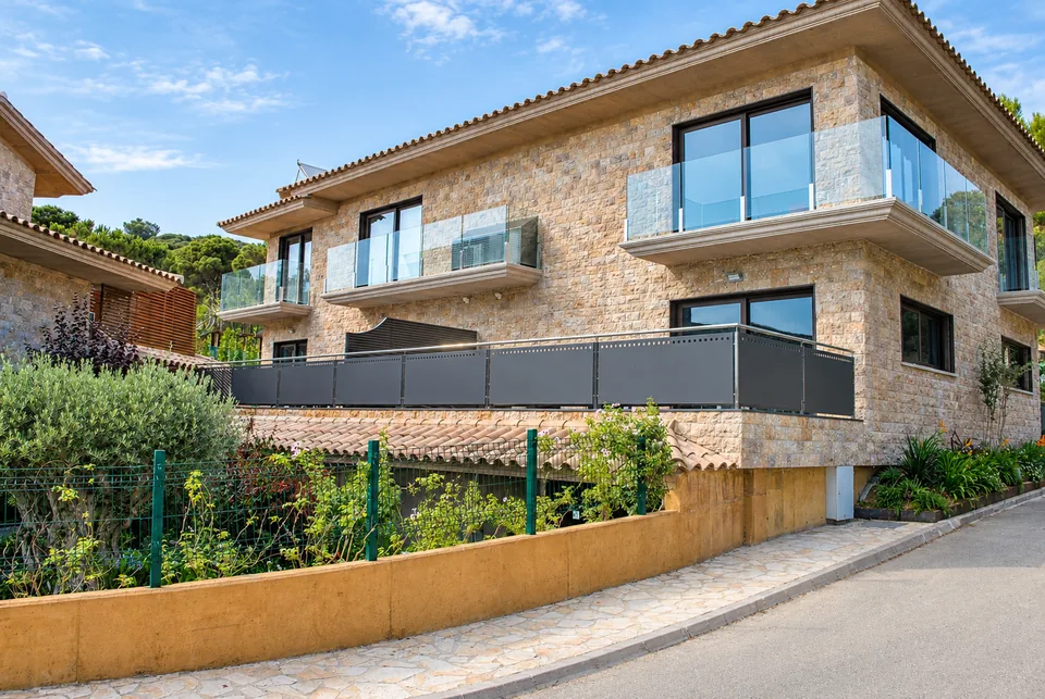 Edifici de les habitacions rurals del Camping King's, amb façana de pedra, balcons de vidre i jardí